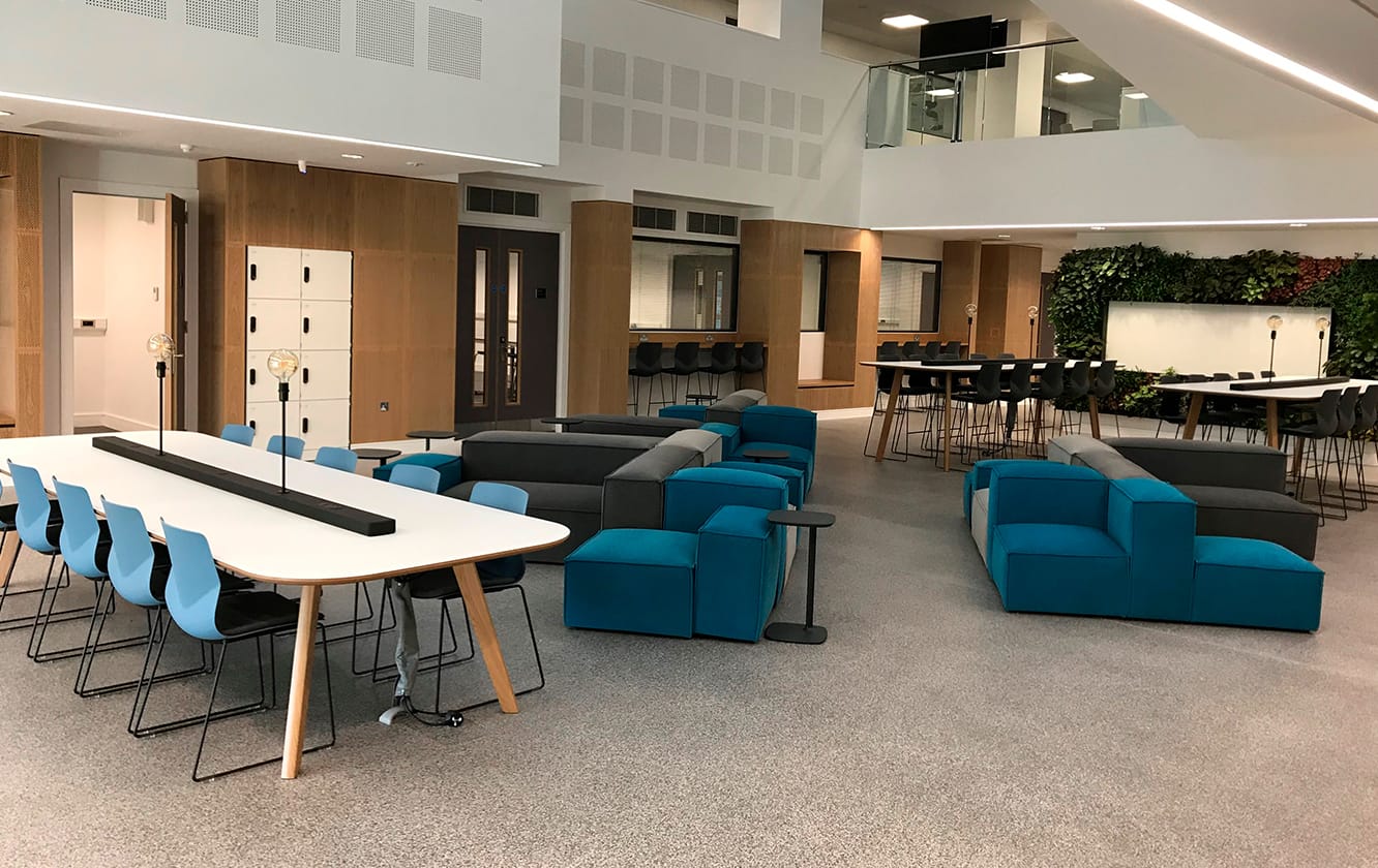 A conference room with blue chairs and tables and modular seating.